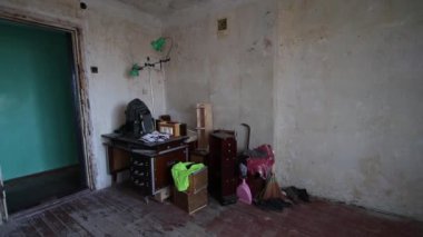 Eski yıkılmış ortak oda. Olgun bir adam eski bir buzdolabını bir apartmanın harabelerinde balyozla yıkar.