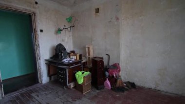 Eski yıkılmış ortak oda. Olgun bir adam eski bir buzdolabını bir apartmanın harabelerinde balyozla yıkar.