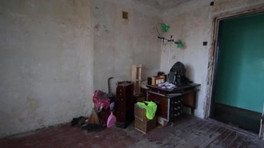 Eski yıkılmış ortak oda. Olgun bir adam eski bir buzdolabını bir apartmanın harabelerinde balyozla yıkar.