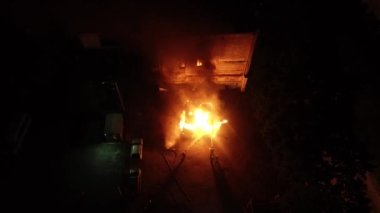 A car is burning and gasoline is dripping and burning. Unrecognizable firefighter spraying water and foam for extinguishing the fire. Loopable seamless animation cinemagraph