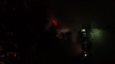 A car is burning and gasoline is dripping and burning. Unrecognizable firefighter spraying water and foam for extinguishing the fire. Loopable seamless animation cinemagraph