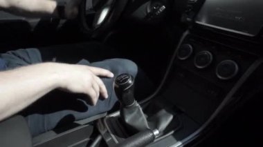 Man in warm clothes changing gear during car driving, mechanical speed control at day. Bunch of keys dangling at drive. Inside of car, focus on shift lever of manual transmission and hand. Riding auto