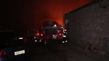 Şehir caddesinde yangın söndürücüyle yangını söndürmeye çalışan ama içerisi tamamen yanmış bir araba yangını.