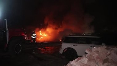 Şehir caddesinde yangın söndürücüyle yangını söndürmeye çalışan ama içerisi tamamen yanmış bir araba yangını.