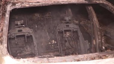 Şehir caddesinde yangın söndürücüyle yangını söndürmeye çalışan ama içerisi tamamen yanmış bir araba yangını.