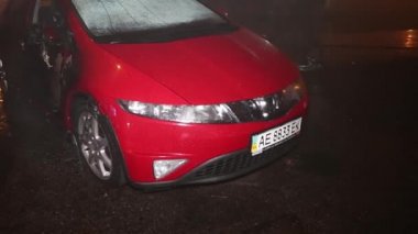 Şehir caddesinde yangın söndürücüyle yangını söndürmeye çalışan ama içerisi tamamen yanmış bir araba yangını.