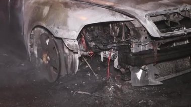 Şehir caddesinde yangın söndürücüyle yangını söndürmeye çalışan ama içerisi tamamen yanmış bir araba yangını.