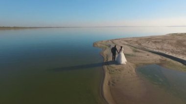 Gelin ve damat sahil boyunca yürüyerek. Hava