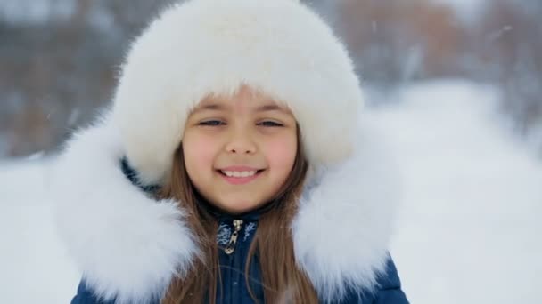 Mädchen mit weißem Pelzmütze an einem Wintertag. — Stockvideo