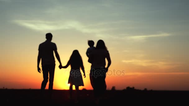 Silhueta da família caminhando juntos ao pôr do sol — Vídeo de Stock