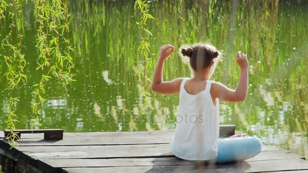 Giovane ragazza rilassante meditando sul lago — Video Stock