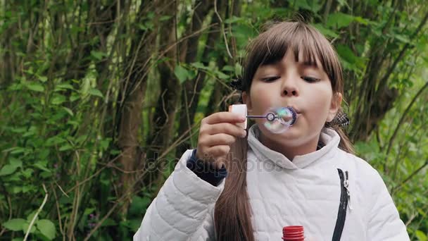 Menina sopra bolhas de sabão — Vídeo de Stock