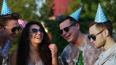 Yaz partisinde bir grup arkadaş, bira şişeleriyle yakın plan çekimde doğum gününü kutluyor.