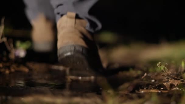 Hombre misterioso camina a la distancia en la oscuridad, pisando el barro y charco, de cerca — Vídeo de stock