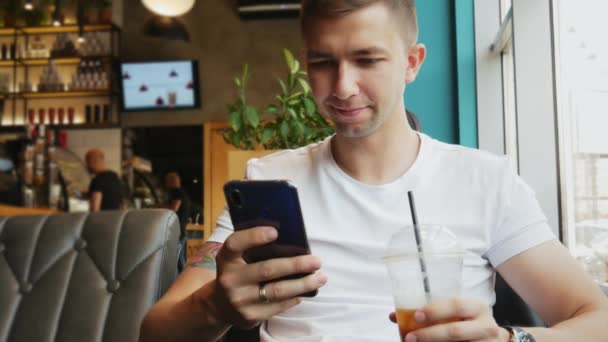 Primer plano retrato de un hombre joven utilizar el teléfono móvil en la cafetería — Vídeos de Stock