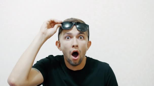 Een jonge man is zeer geschokt en verrast, houdt zijn hoofd — Stockvideo