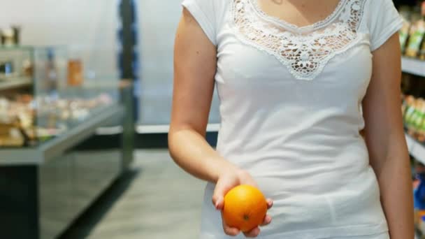 Женская рука бросает разноцветный апельсин в супермаркете в замедленном темпе — стоковое видео