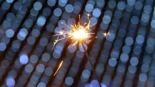 Close-up van vuurwerk sterretje branden met blauwe bokeh lichten van slinger — Stockvideo