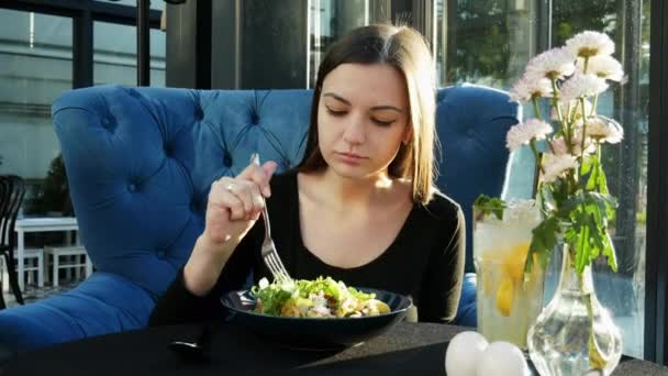 Allein schöne junge Frau isst einen heißen Salat in einem Restaurant allein bei Sonnenuntergang — Stockvideo