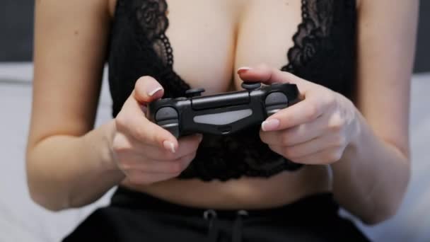 Крупный план сексуальной неузнаваемой женщины в кружевном лифчике с великолепной грудью, играющей в игры на консоли на геймпаде — стоковое видео