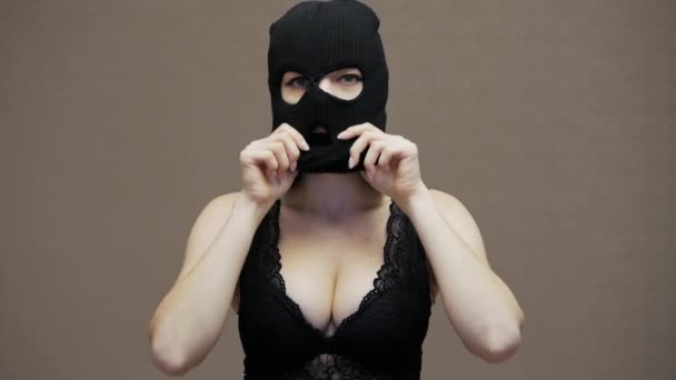 Сексуальная смешная женщина надевает хакеру черную маску балаклавы, одевается в кружевной бюстгальтер, грабит — стоковое видео