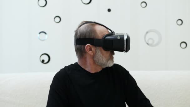 Middle-aged man with grey beard use VR headset and looking around — ストック動画