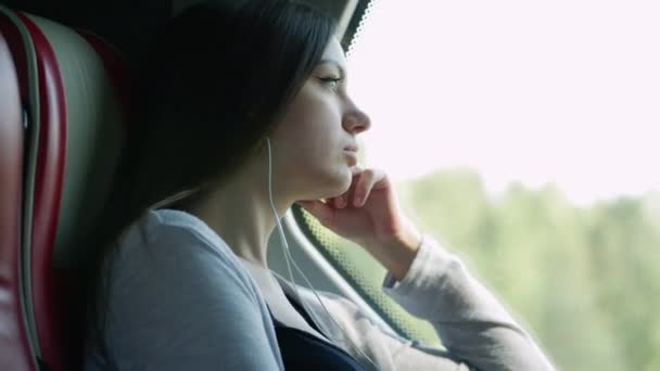 Porträt einer einsamen Frau, die im Bus reist, wehmütig auf Fenster blickt und Musik hört — Stockvideo