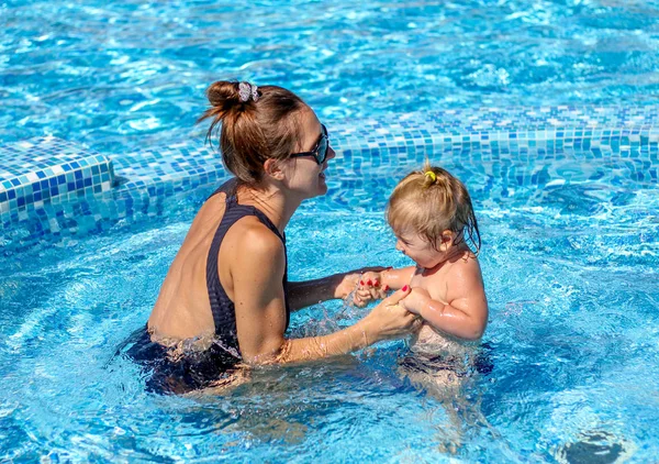 Baby girl learn to swim in pool  with her mother
