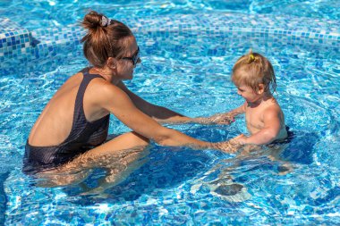 Kız bebek annesiyle havuzunda yüzmeyi öğrenmek