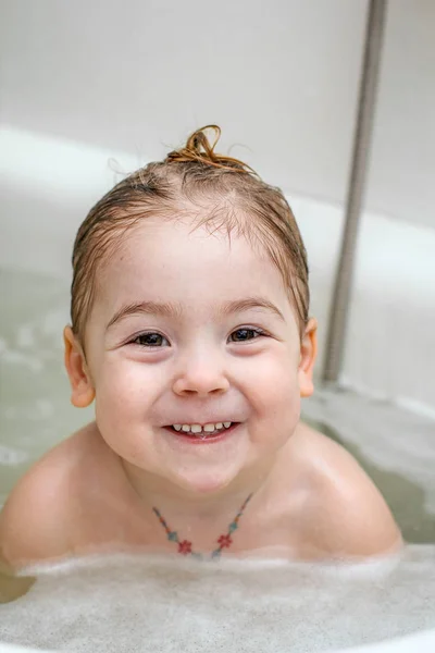 A Little Girl Makes Funny Faces In The Bath Foam Shower Stock Photo