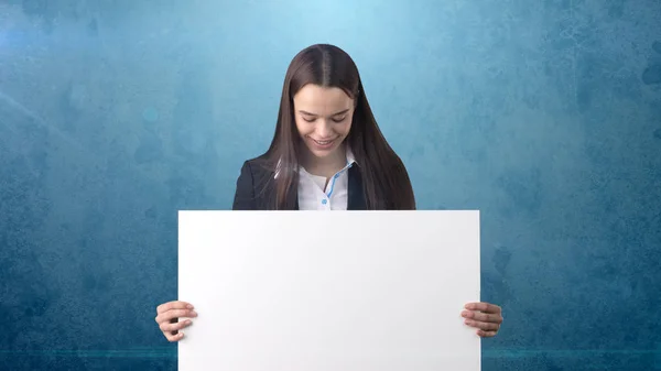 Leende Business kvinna stående med tomma vita ombord på blå isolerade. Kvinnlig modell med långt hår. — Stockfoto