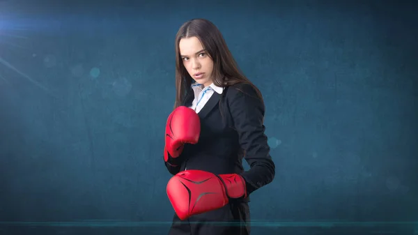 Jovem mulher bonita em terno preto e camisa branca em pé em pose de combate com luvas de boxe vermelho. Conceito de negócio . — Fotografia de Stock