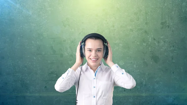 Mujer de negocios en falda blanca relajante escuchando música en auriculares estéreo con sonrisa dichosa. Fondo aislado  . — Foto de Stock