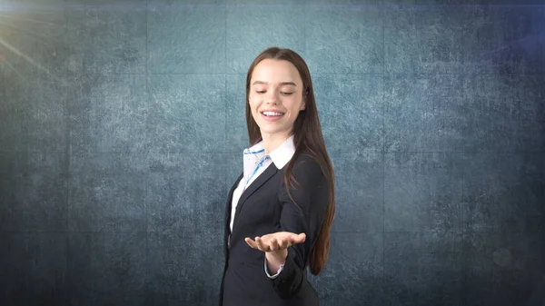 Belle femme d'affaires brune souriante à cheveux longs montrant quelque chose d'invisible devant elle avec copyspace — Photo