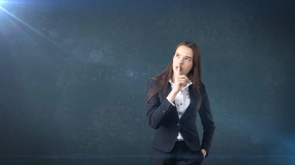 Joven mujer de negocios retrato en traje de pie y el dedo cerca de sus labios con signo de silencio, fondo con copyspace . — Foto de Stock