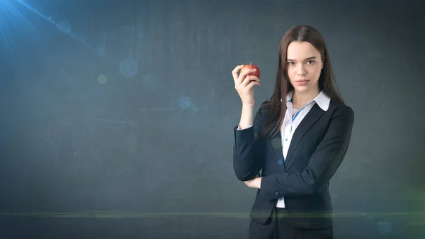 Girl in suit holds bright vibrant apple in hand, symbolising new ideas and fresh concepts or healthy lifestyle in office — Stock Photo, Image