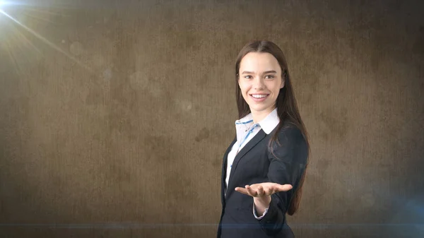 Bella sorridente donna d'affari bruna longhair che mostra qualcosa di invisibile di fronte a lei con copyspace — Foto Stock