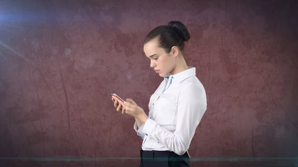 Νέοι χαριτωμένο επιχειρηματίας κοντινό πορτρέτο κρατώντας το κινητό στα χέρια της και να το παρακολουθούν. Φόντο απομονωμένες στούντιο — Φωτογραφία Αρχείου