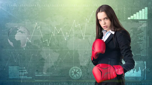 Young beautiful woman dress in suit standing in combat pose with red boxing gloves. Business concept.