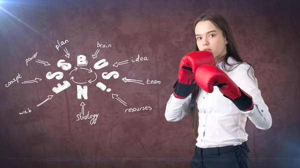 Mulher de luvas de boxe vermelho em pé perto da parede com um esboço de ideia de negócio desenhado nele. Conceito de um negócio bem sucedido . — Fotografia de Stock