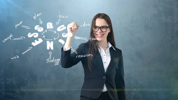 Chica de belleza en un traje de pie cerca de la pared y escribir un boceto idea de negocio dibujado en él. Concepto de mujer exitosa . — Foto de Stock