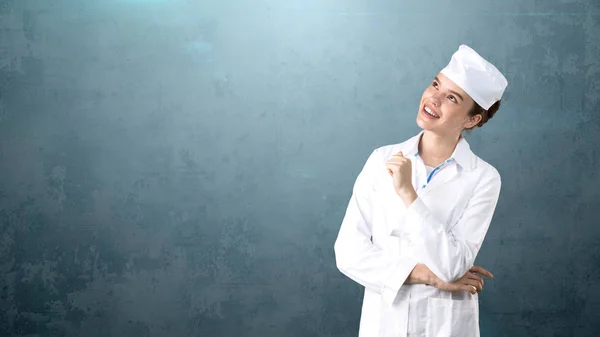 Bella dottoressa in uniforme. Studio dipinto sfondo. Concetto di assistenza sanitaria redditizia . — Foto Stock