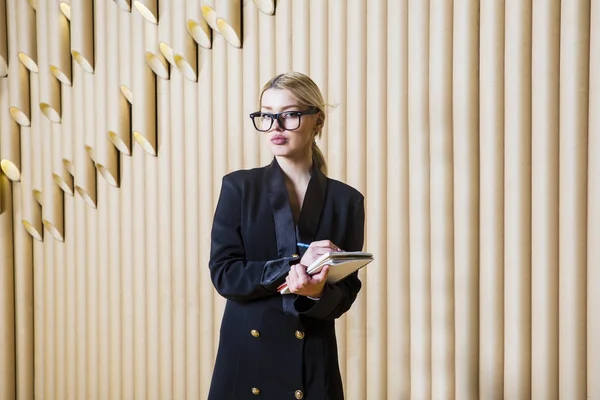 Beautiful amazed blonde business woman in black dress and glasses.
