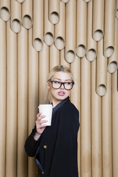 Hermosa mujer de negocios rubia sorprendida en vestido negro y gafas con taza de café . — Foto de Stock