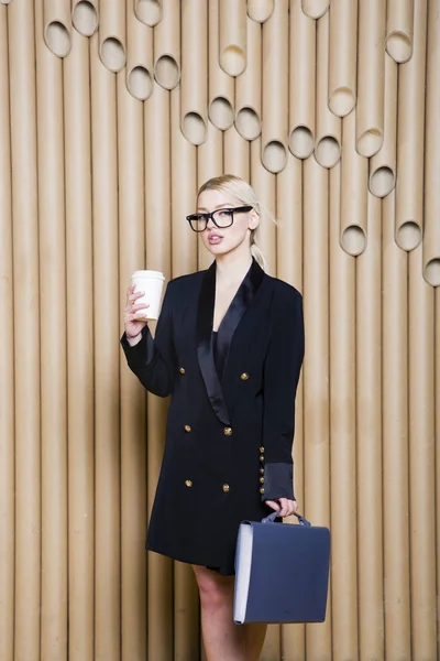 Όμορφη κατάπληκτος ξανθιά γυναίκα στο μαύρο φόρεμα και γυαλιά με κούπα καφέ. — Φωτογραφία Αρχείου