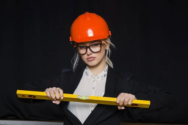 Hermosa mujer de negocios rubia con nivel de aplicación en la oficina loft en casco de construcción naranja y traje . — Foto de Stock