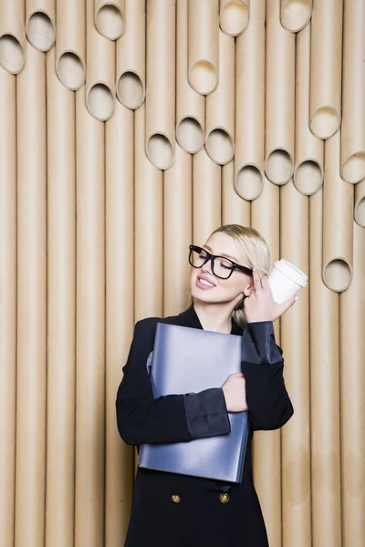 Beautiful amazed blonde business woman in black dress and glasses with coffee mug.