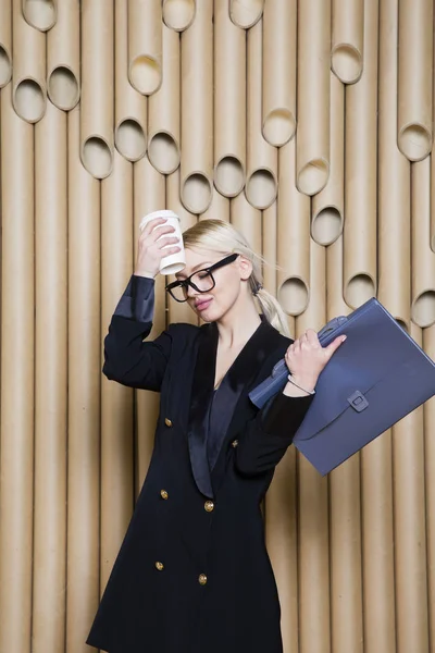 Hermosa mujer de negocios rubia sorprendida en vestido negro y gafas con taza de café . — Foto de Stock