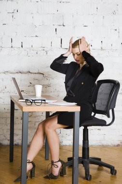 Genç sarışın güzel işkadını dizüstü bilgisayar, dizüstü bilgisayar ve gözlük kıyafetli bir office masada oturuyor. İş kavramı.