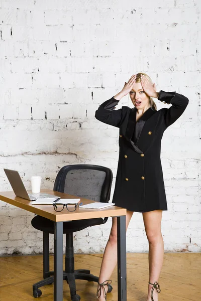 Giovane donna d'affari di bellezza bionda seduta a un tavolo da ufficio con laptop, notebook e occhiali in giacca e cravatta. Concetto aziendale . — Foto Stock